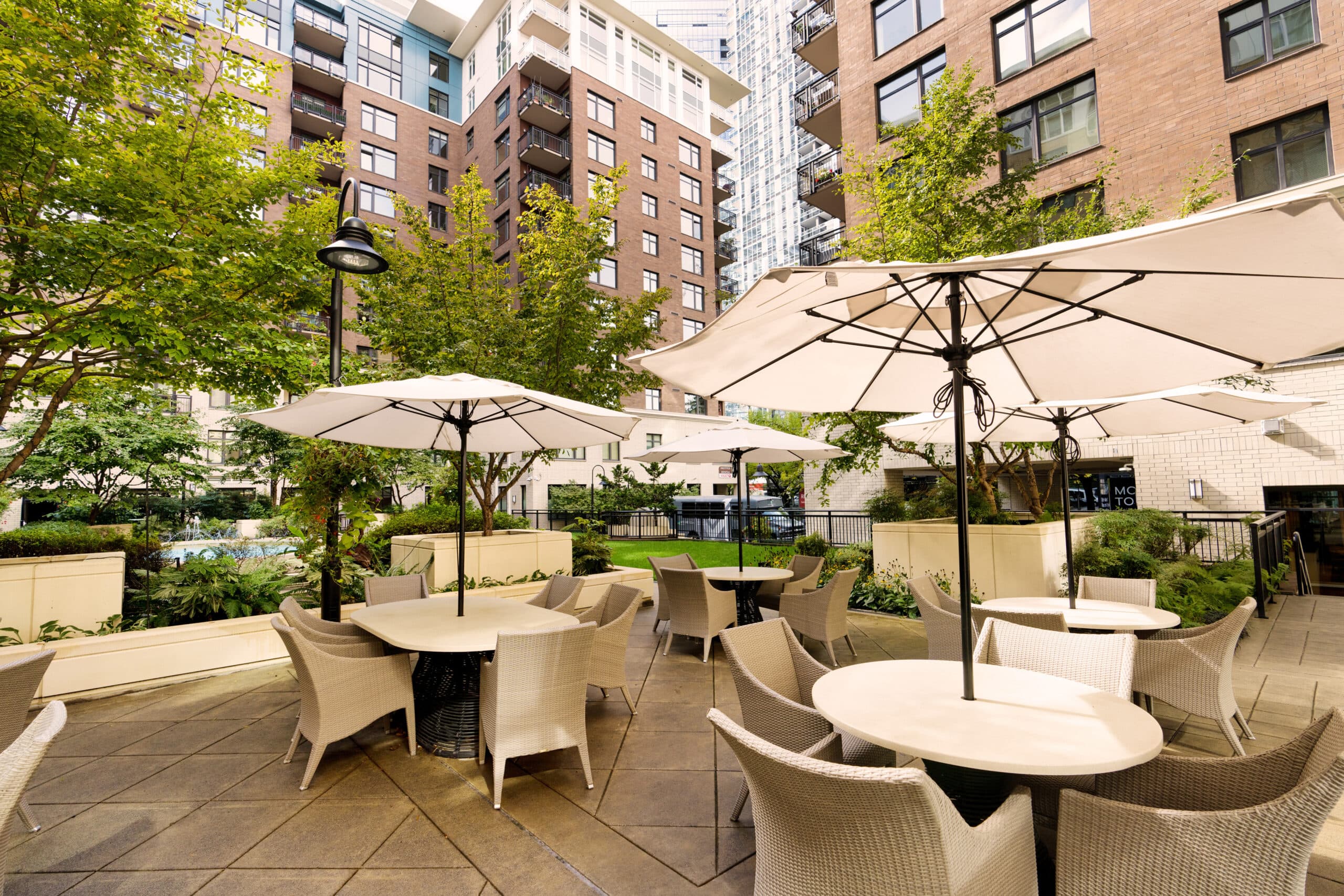 A courtyard near the Mirabella Seattle residences with tables and umbrellas for shade.